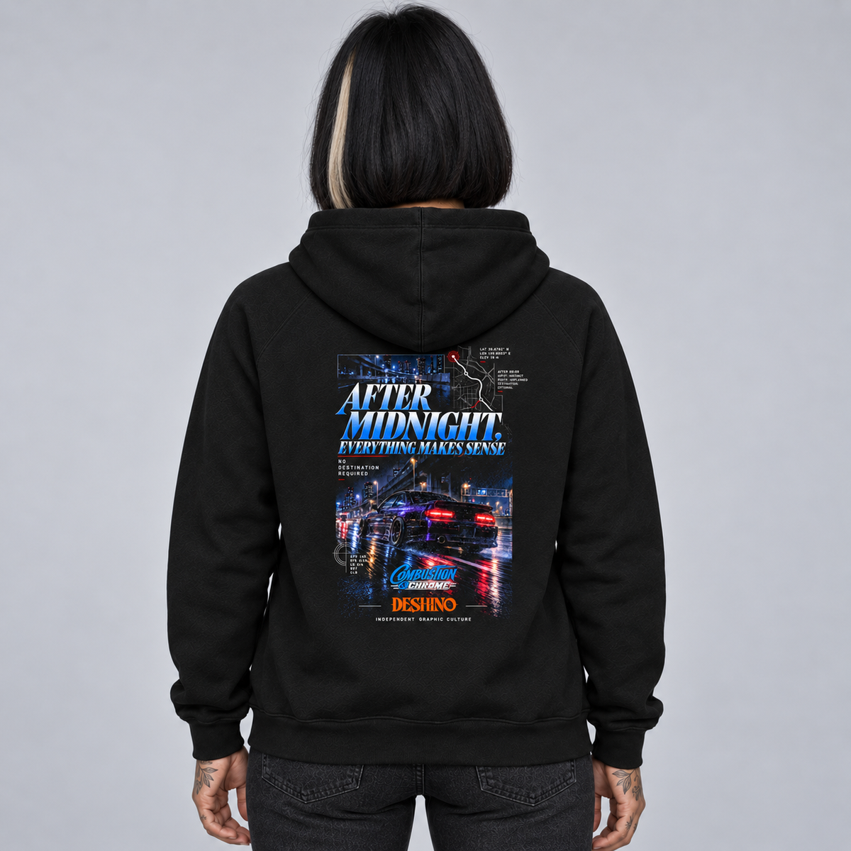 A person shown from the back wearing a Deshino black hoodie with a large graphic print on the back. The graphic features the text 'AFTER MIDNIGHT EVERYTHING MAKES SENSE' above a nighttime city street scene with blue and orange lighting.