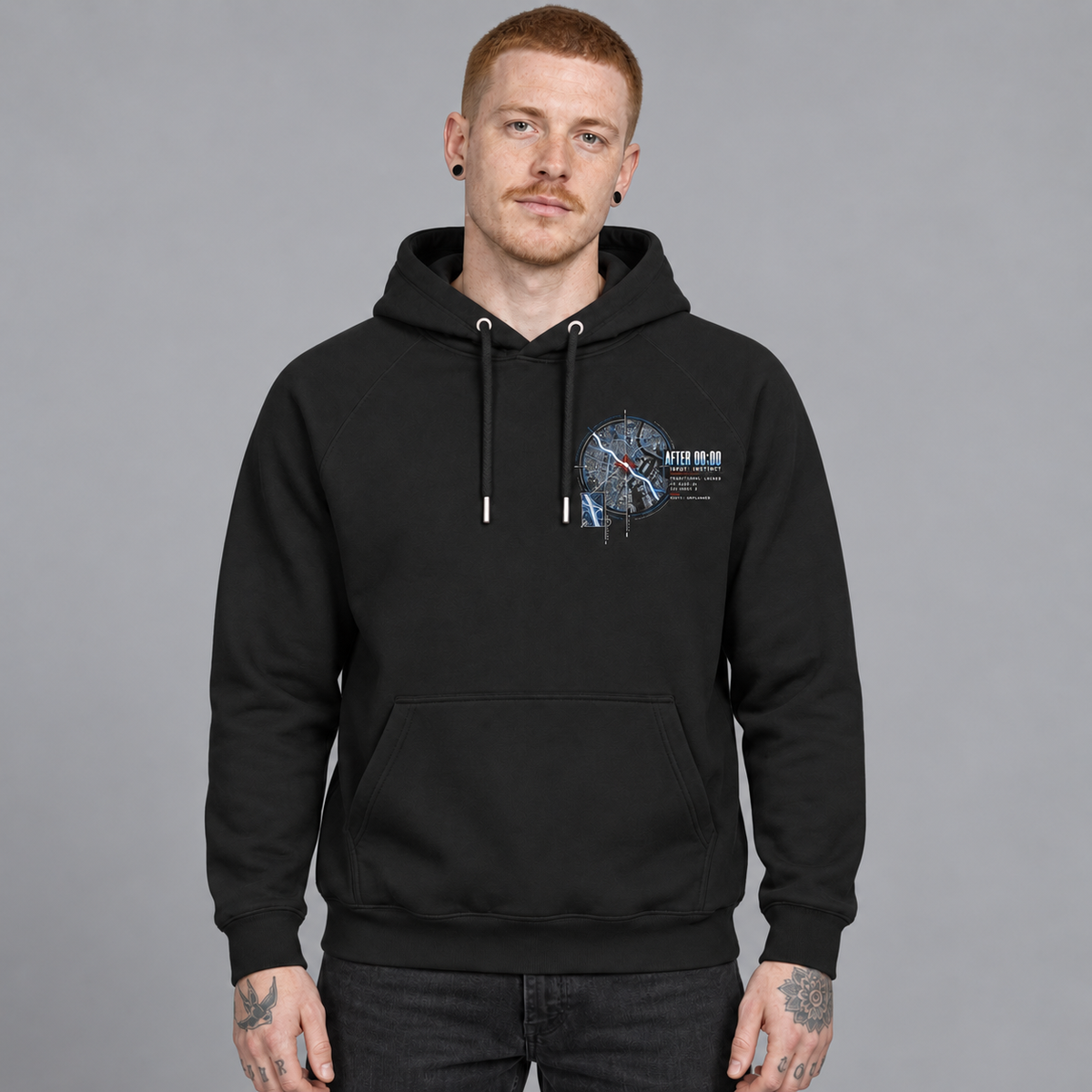 A man wearing a Deshino black pullover hoodie with a blue and white graphic print on the left chest, standing against a solid grey studio background.