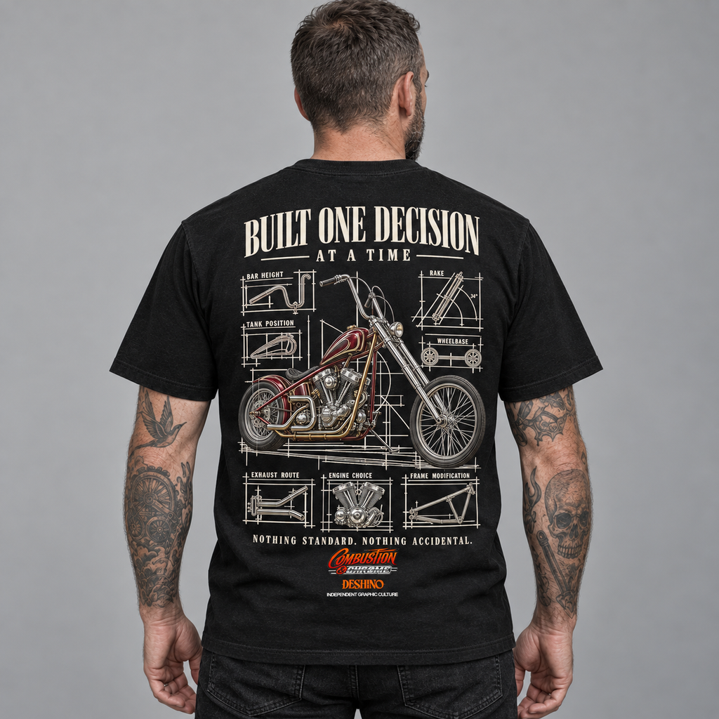 A man viewed from behind wearing a black graphic t-shirt. The back of the shirt features a large white and red technical blueprint-style illustration of a chopper motorcycle, with the text 'BUILT ONE DECISION AT A TIME'.