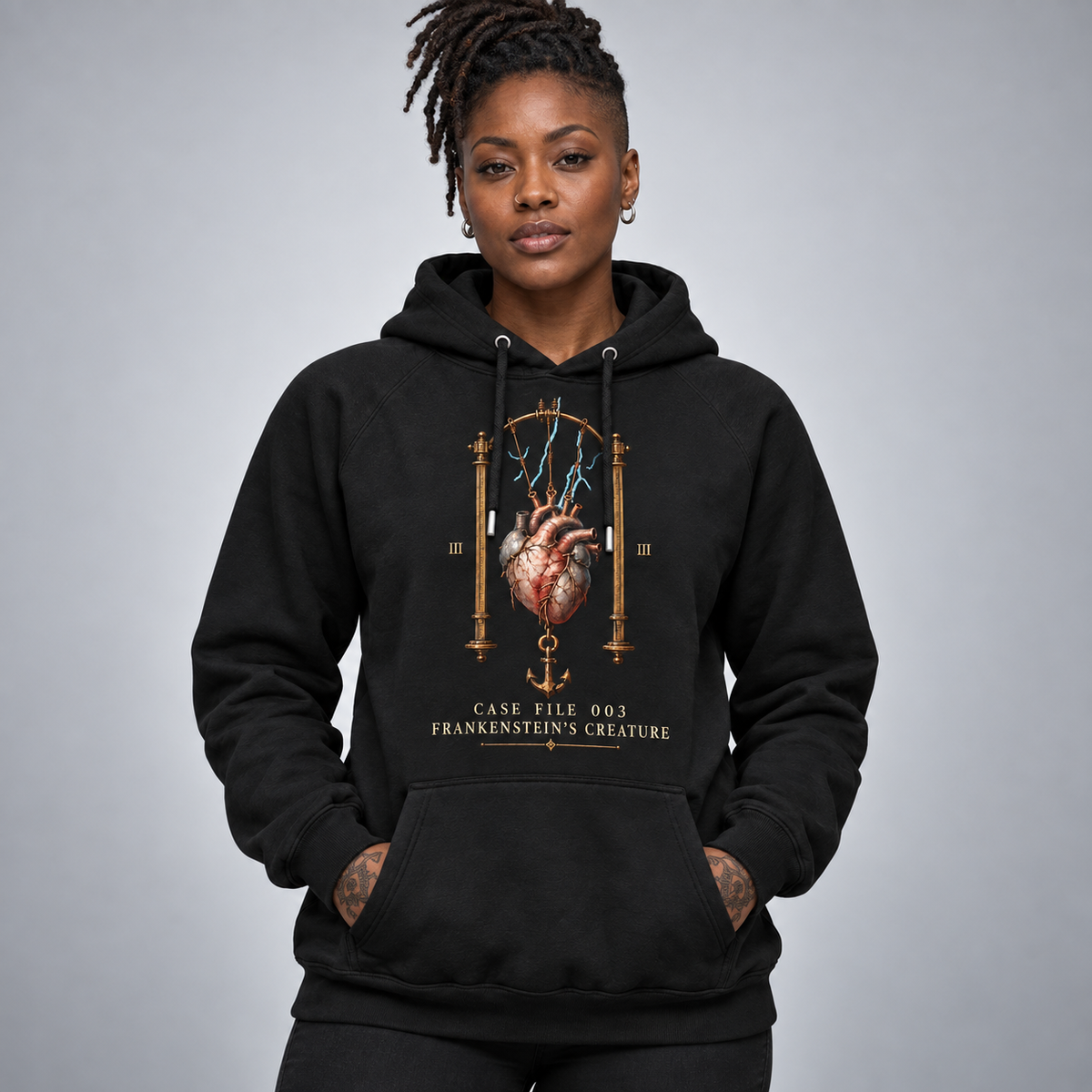 A woman wearing a black pullover hoodie with a detailed graphic print on the front. The graphic features an anatomical heart with lightning, Roman numerals, and the text 'CASE FILE 003 FRANKENSTEIN'S CREATURE'.
