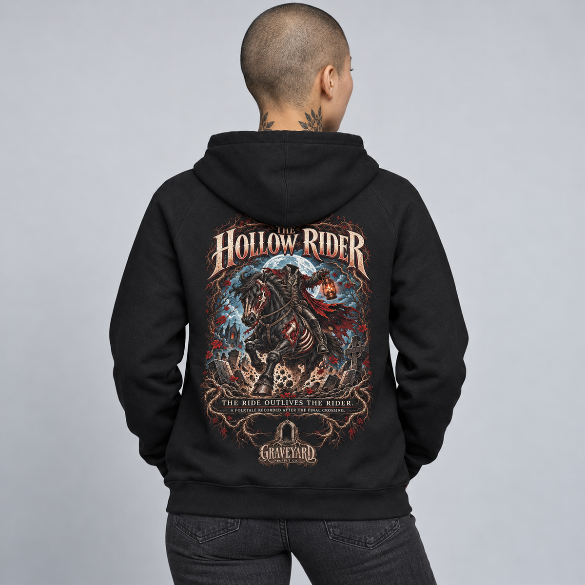 A person shown from the back wearing a black hoodie with a large detailed graphic print on the back. The graphic features the text 'HOLLOW RIDER' and 'THE RIDE OUTLIVES THE RIDER' with an illustrated skeletal rider on a horse against a blue and red background.