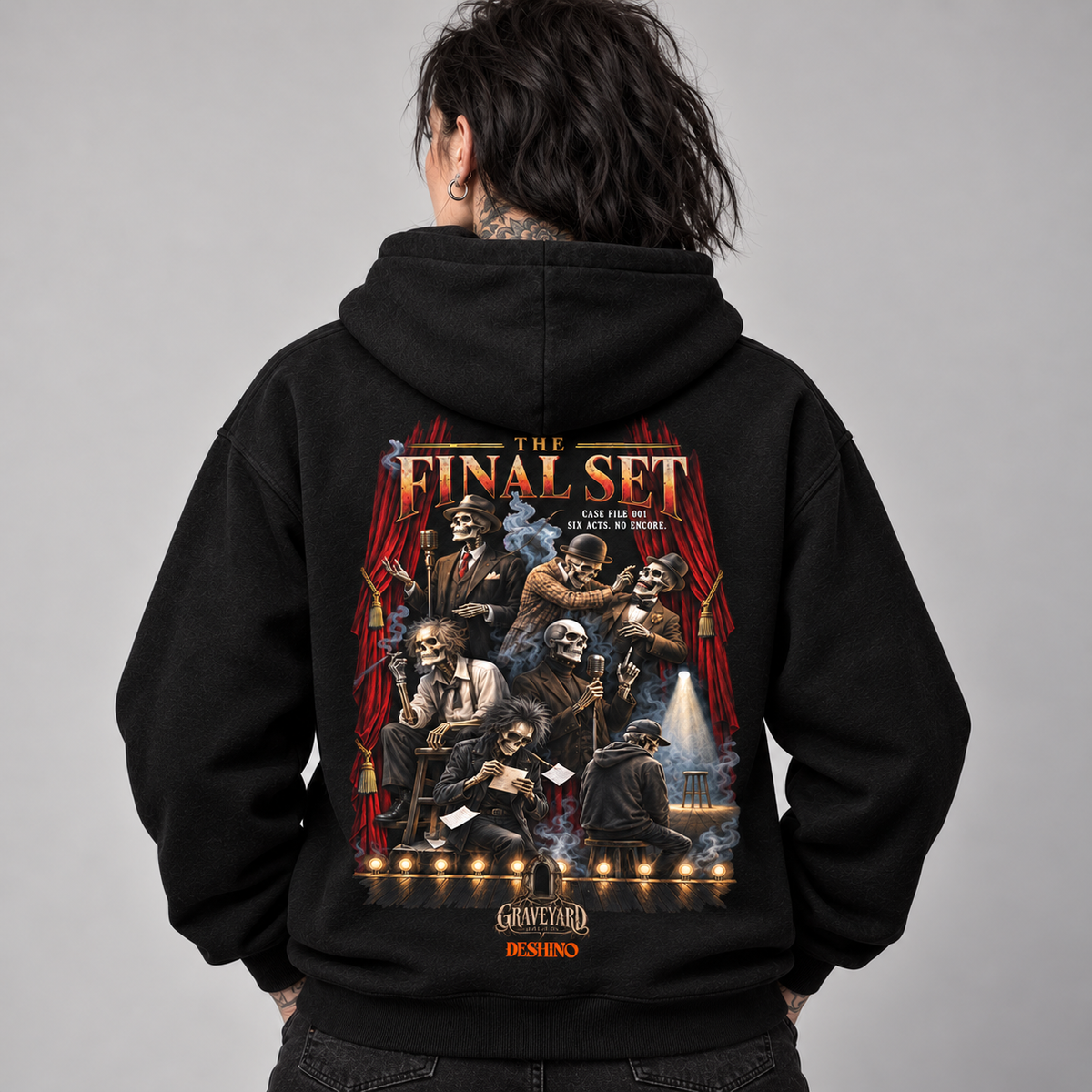 A person shown from behind wearing a black hoodie with a large, detailed graphic print on the back. The graphic features the text 'THE FINAL SET' with illustrations of dead comedians and red curtains, set against a plain gray studio background.