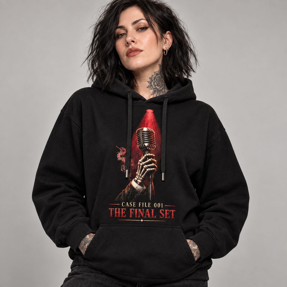 A woman wearing a black pullover hoodie with a graphic print of a skeleton hand holding a red microphone and the text 'CASE FILE 001 THE FINAL SET'.