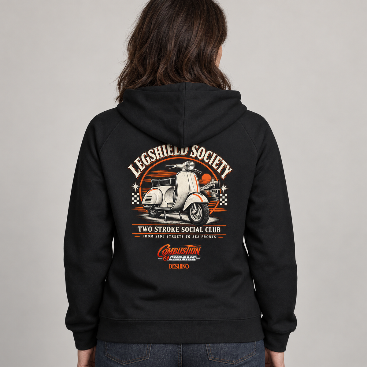 A person shown from the back wearing a black hoodie with a large vintage-style graphic on the back. The graphic features a white scooter, orange and cream text reading 'Legshield Society' and 'Two Stroke Social Club,' plus smaller red and orange branding near the bottom.