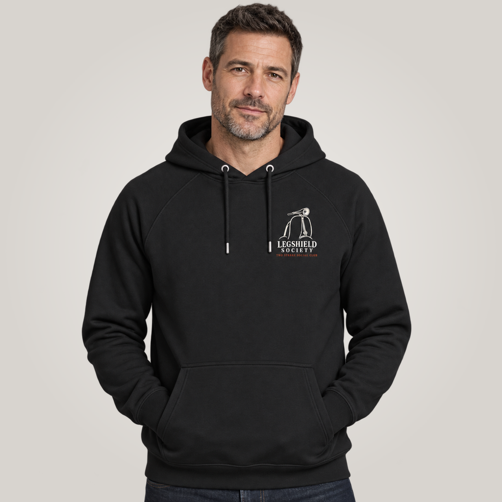 A man wearing a black pullover hoodie with a white 'Legshield Society' logo on the left chest, set against a plain light gray studio background.