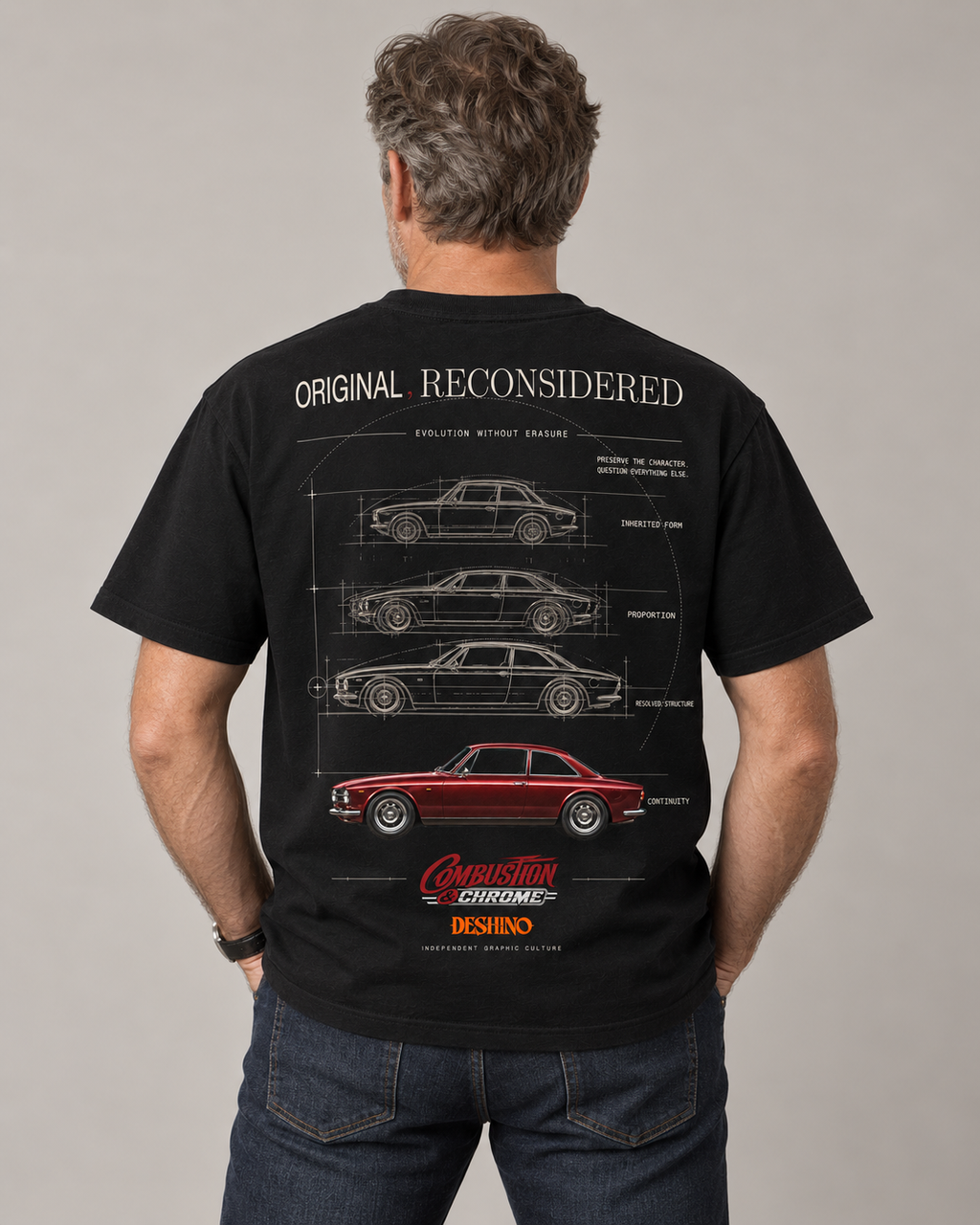 A man viewed from behind wearing a black graphic t-shirt with a detailed car patent drawing and a red classic car illustration on the back. The t-shirt features the text 'ORIGINAL RECONSIDERED'.