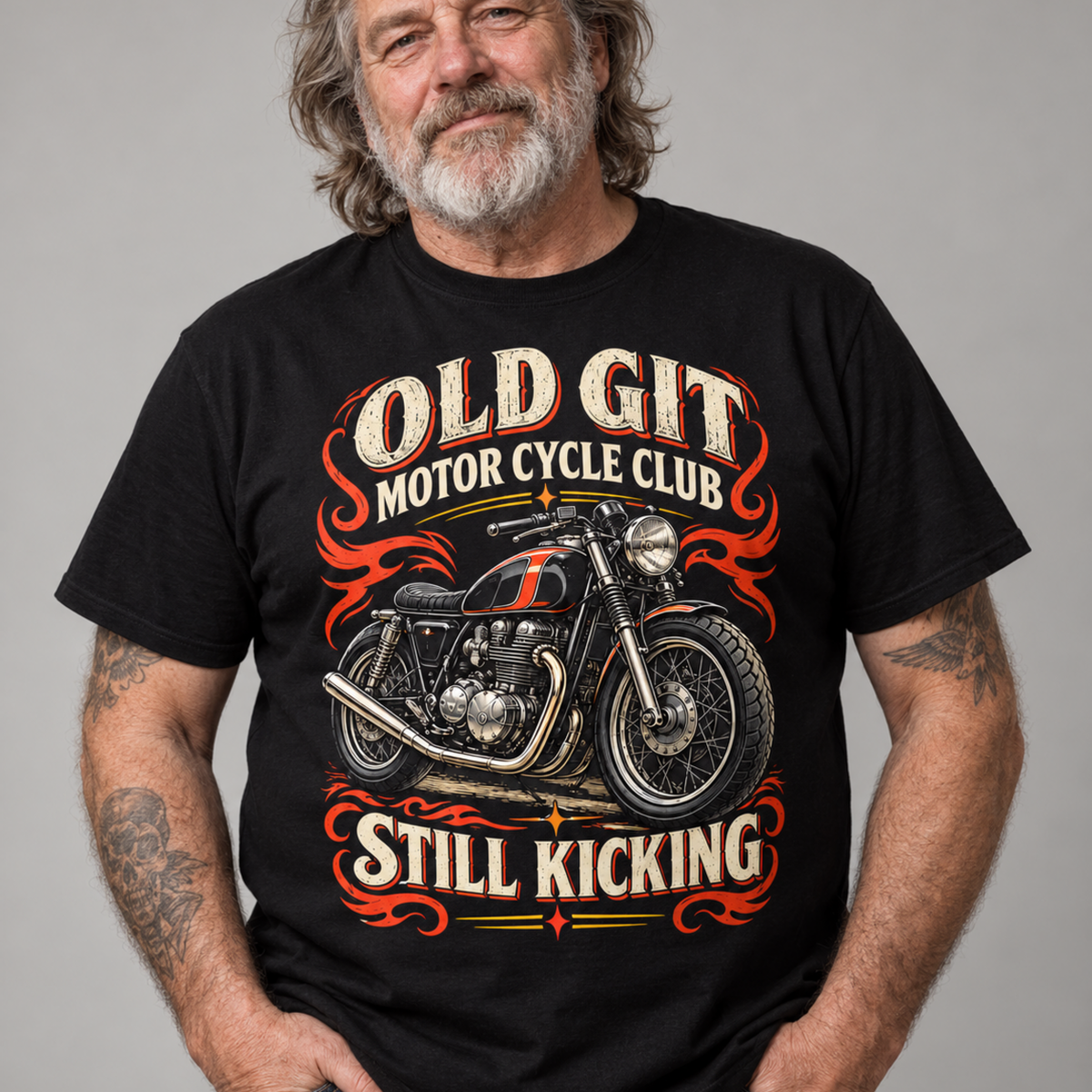 A man wearing a black graphic t-shirt with a vintage-style motorcycle print and the text 'OLD GIT MOTOR CYCLE CLUB' and 'STILL KICKING'.