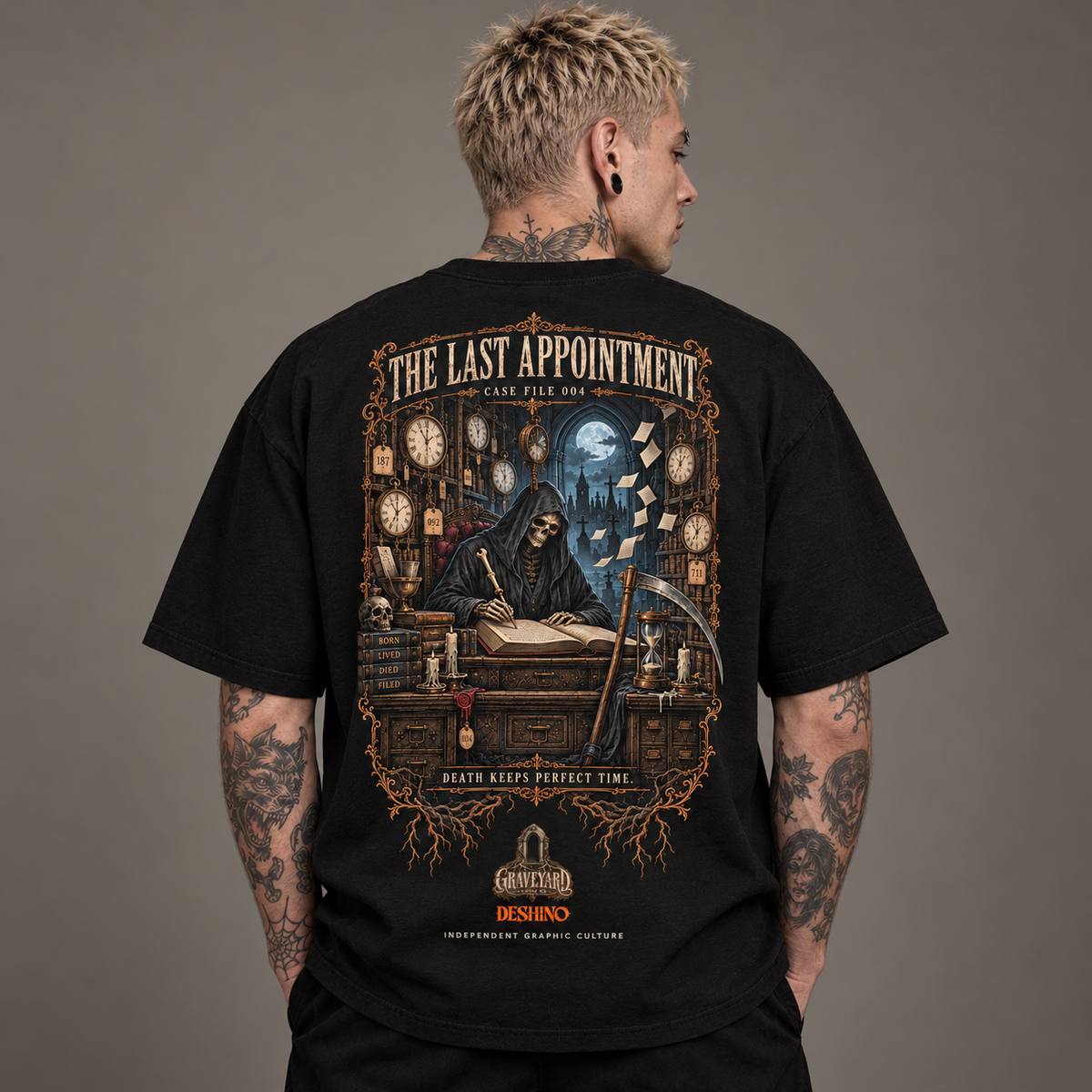 A man viewed from behind wearing a black graphic t-shirt. The shirt features a large, detailed gothic illustration of a grim reaper at a desk with clocks and the text 'THE LAST APPOINTMENT' and 'CASE FILE 004'.