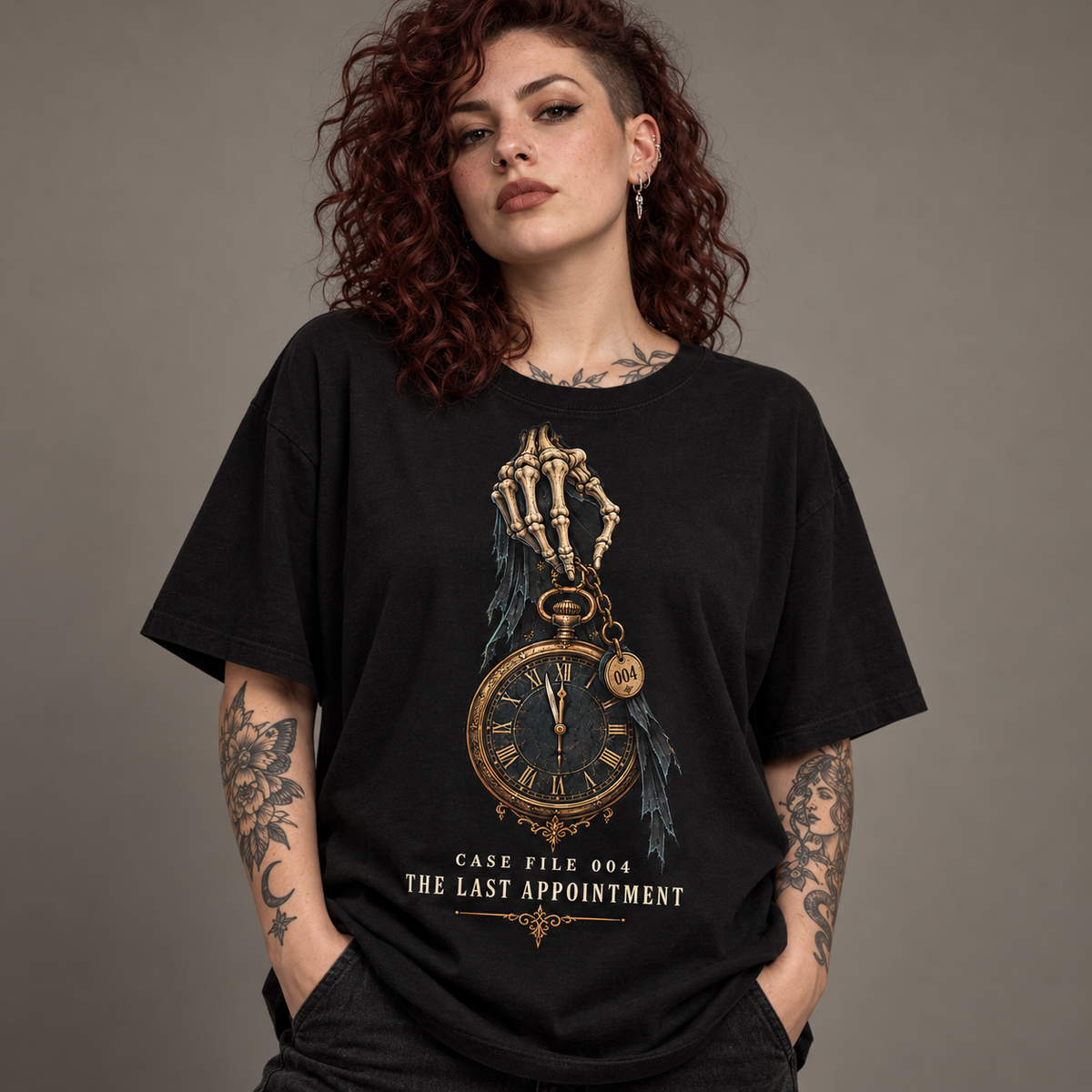 A woman with curly red hair and tattoos wears an oversized black graphic T-shirt featuring a skeleton hand holding a gold pocket watch with the text 'CASE FILE 004 THE LAST APPOINTMENT'.