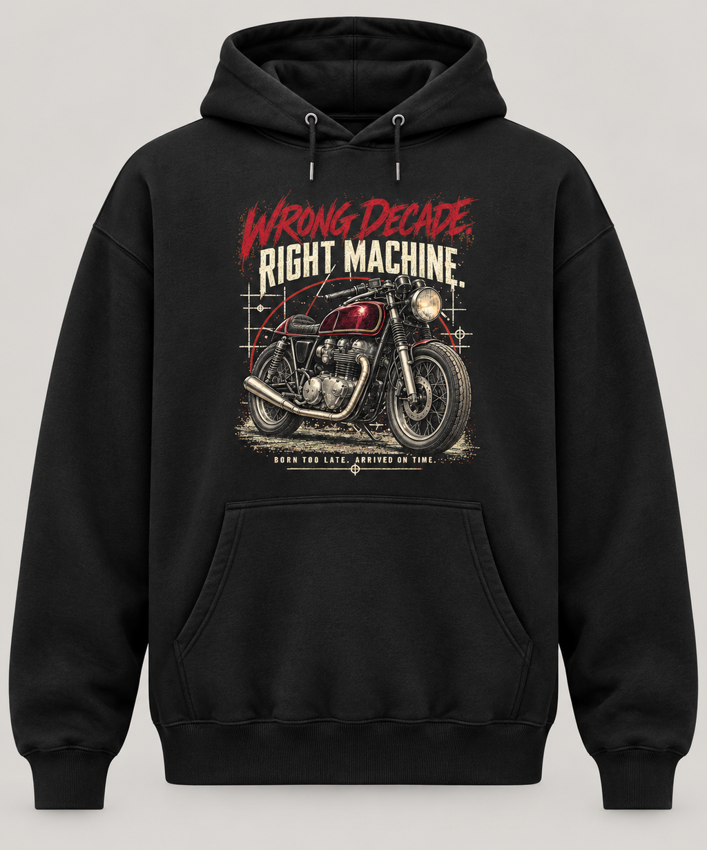 A black pullover hoodie with a graphic print of a vintage motorcycle and the text 'WRONG DECADE RIGHT MACHINE' on the front, shown against a neutral light grey background.